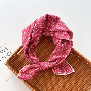 Dettaglio della sciarpa in cotone rosa con stampe di fiori e uccelli bianchi