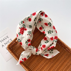Detailed view of lightweight red floral cotton linen scarf on a brown woven tray