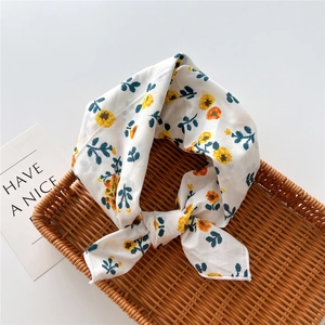 Detail view of white floral scarf with yellow flowers tied in a bow inside a basket