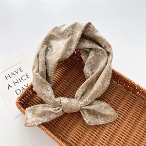 Detail of floral cotton linen neckerchief with knot design on a woven tray
