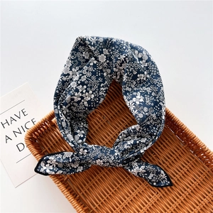 Close-up of a navy blue floral scarf with a knot detail on a rustic wicker tray
