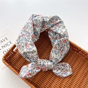 Foulard in cotone a fiori rossi e blu presentato in un cesto di vimini rustico