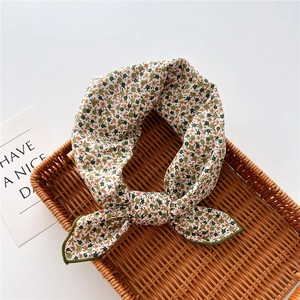 Close-up of a floral cotton linen scarf tied in a bow on a woven rattan tray