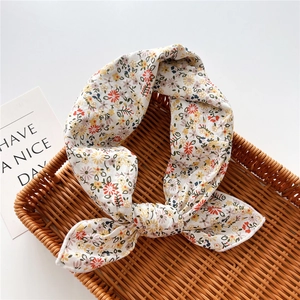 Dettaglio di un foulard in cotone e lino a fiori con nodo a torsione in un cesto intrecciato