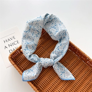 Detail of blue floral cotton linen scarf with elegant knot in a rustic woven tray