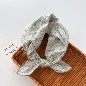 Detailed view of floral cotton neckerchief on a rustic woven basket with a card