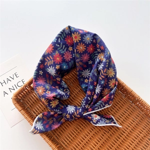 Detail of navy floral cotton linen scarf tied in a bow on a natural wicker tray