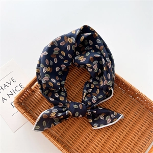 Detail of navy blue cotton-linen scarf featuring autumn leaf prints and fine white stitching