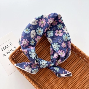 Close-up of a dark blue cotton floral headband with cat print in a woven tray