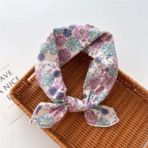 Detail of cotton linen scarf with floral cat print on a rustic woven tray
