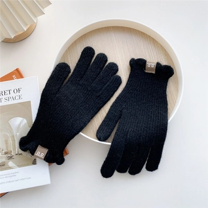 Close-up of thick black knitted gloves with wavy cuffs and premium brown leather label