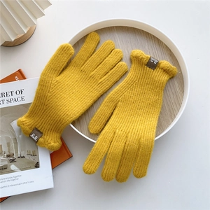 Detailed close-up of ginger yellow knitted winter gloves with ribbed texture and brand label