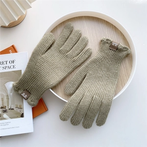 Detail of olive green knit gloves featuring ribbed cuffs and a brown leather logo patch