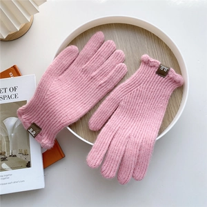 Detail of pink knitted gloves with thick ribbed texture and leather logo patch