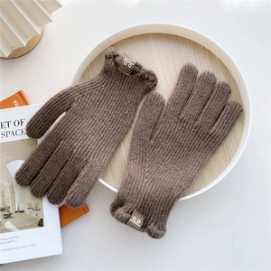 Detailed knit texture of dark coffee winter gloves with stylish brand label