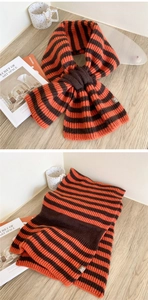 Dettaglio di sciarpa in maglia a righe arancio e marrone con chiusura a incrocio