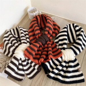 Sciarpe a maglia a righe in tre colori con etichetta in pelle su sfondo legno