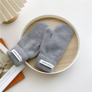 Detail of grey thick thermal mittens with Hand Made label on a wooden tray