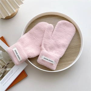 Close-up of pink knitted mittens with soft texture and Hand Made label detail