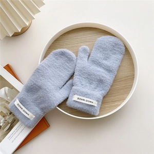 Close-up of light blue knitted mittens with handmade label on a wooden tray