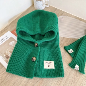 Detail of green knit hooded scarf with thick texture and wooden buttons on wooden table