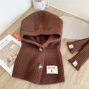 Close-up of brown knitted balaclava hood with arm warmers on a wooden surface
