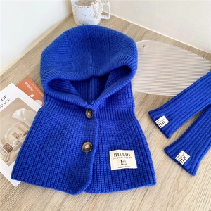 Detail of royal blue knitted hooded scarf set with buttons on light wooden desk background