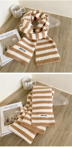 Detail of striped knit scarf with BRICK logo patch on soft brown and cream fabric