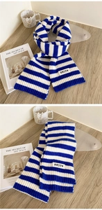 Detail of blue and white striped knit scarf with BRICK woven patch on a soft texture