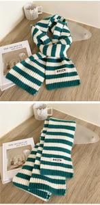 Detail of green and white striped knit scarf with BRICK patch on wooden background
