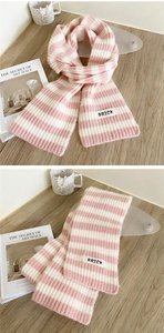 Detail of pink and white striped knit scarf featuring a modern brick letter fabric label