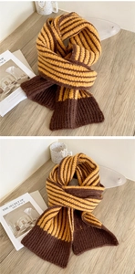 Close-up of thick striped knit scarf in yellow and brown on a rustic wooden table