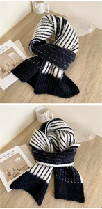 Detail of chunky knit scarf with black and white stripes on a wooden surface