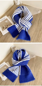 Detailed texture of blue and white striped thick knit scarf on a cozy wooden surface