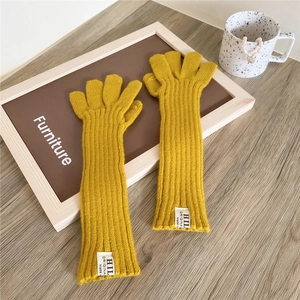 Detail of yellow knit fingerless gloves showing thick ribbed texture and brand label