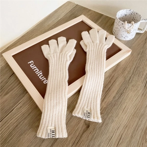 Detailed texture of cream knitted long arm warmers with a stylish label on a wooden desk