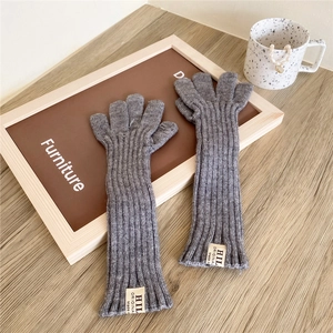 Close-up of grey knit arm warmers with ribbed texture and white brand label detail