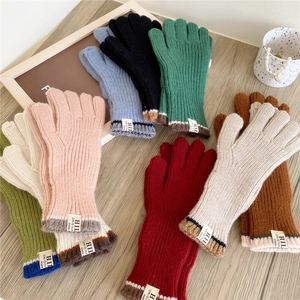Winter knitted touchscreen gloves in various colors on a rustic wooden background