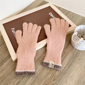 Detail of pink knit gloves featuring dark grey ribbed cuffs and minimalist brand tag