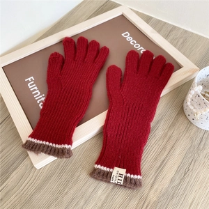Detail of red knitted gloves with two-finger touchscreen design and striped cuffs