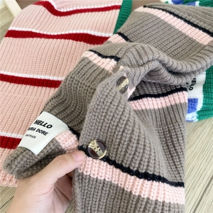 Striped knit hooded scarf with amber buttons and handmade label on wooden background