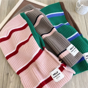 Three striped knitted balaclava hats in various colors on a wooden background
