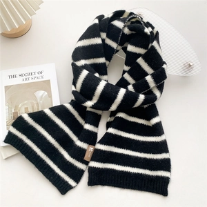 Macro detail of black and white striped knit scarf with a small faux leather brand label