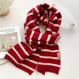 Detail of red and white striped knit scarf with a decorative brown logo patch