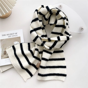 Detail of chunky knit black and white striped scarf with a leather label on a white table