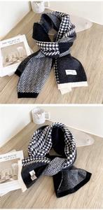 Détail d'une écharpe en maille pied-de-poule noir et blanc avec étiquette sur table bois