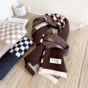 Trois couleurs d'écharpes en maille pied-de-poule en marron, beige et gris sur bois