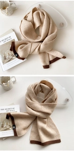 Detailed shot of beige knitted scarf with ribbed edges and black H letter patch