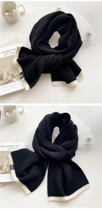 Detailed view of black and white knitted scarf with ribbed edges and thick texture