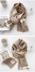 Détail d'une écharpe en maille rayée avec étiquette de marque minimaliste en tissu